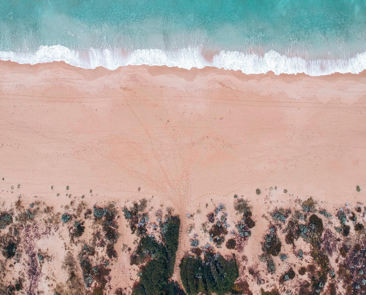 Aerial view of a turquoise coastline meeting pink sand